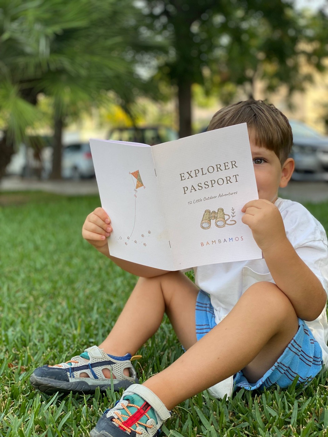 A little explorer sitting on the grass with the Passport open
